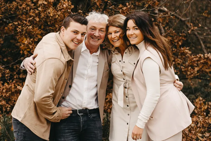 Familie met drie generaties lachend samen in het herfstbos