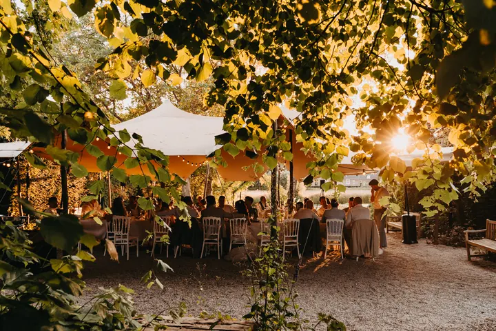 Diner in een tent onder de bomen bij ondergaande zon